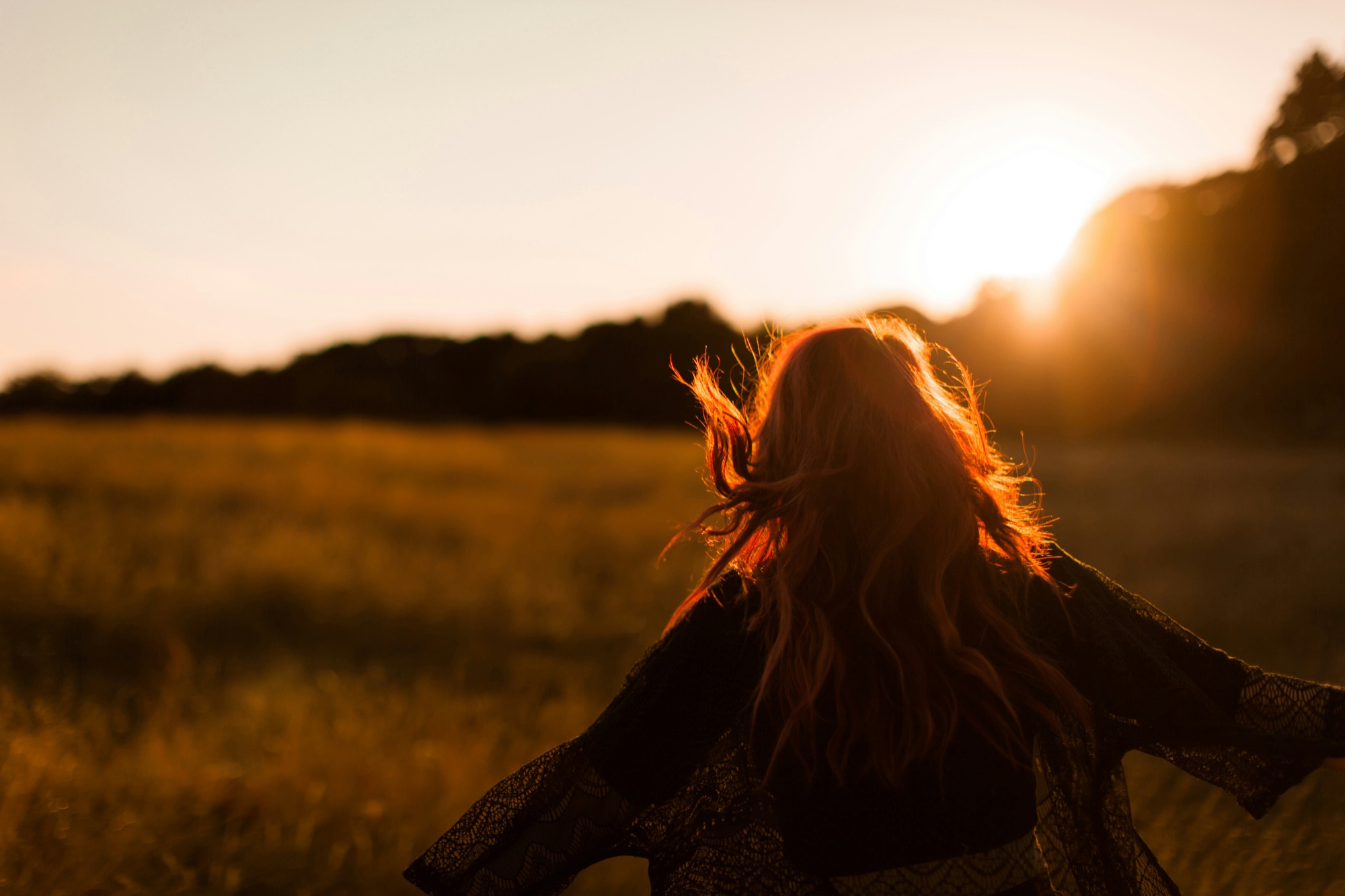 Woman turning toward the sunlight in an open field