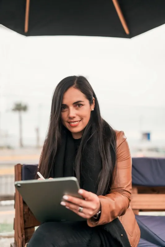 beautiful latin woman working outdoors with a tablet smiling looking at the camera portrait